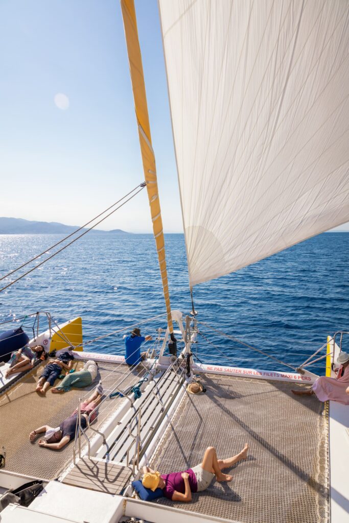 Le catamaran Navivoile naviguant sous gennaker déployé par vent léger avec des passagers se reposant à l'avant lors d'une Sortie bateau Port-vendres