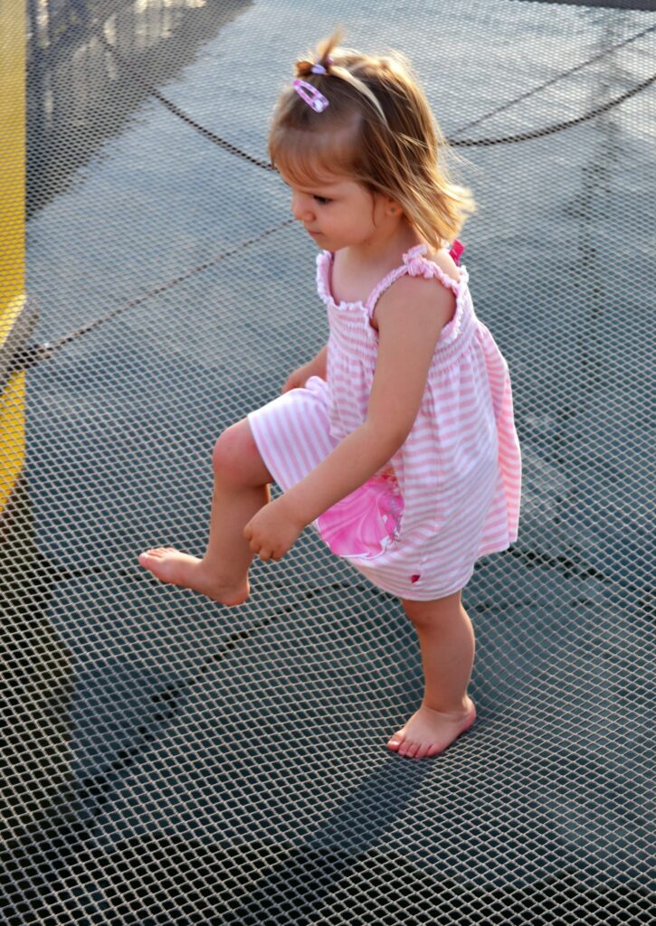 Une petite fille allongée en toute sécurité sur le grand filet à l'avant du catamaran Navivoile, surplombant les eaux turquoise lors d'une Sortie bateau Canet
