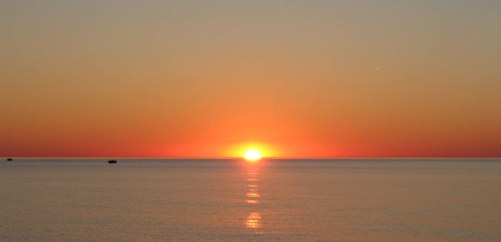 Panorama d'une Sortie en Mer au Lever du Soleil au large de Port-la-Nouvelle. Le ciel est totalement dégagé et sans nuage, offrant une visibilité parfaite sur l'horizon méditerranéen depuis le pont du catamaran Navivoile