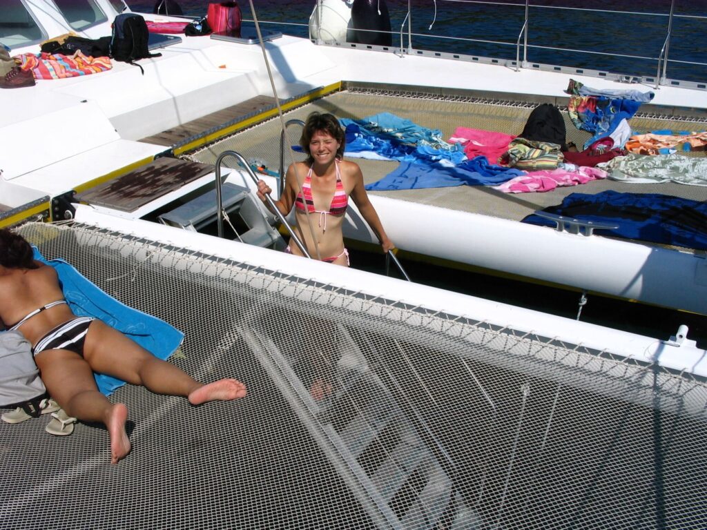 Une passagère empruntant l'escalier de bain à l'avant du catamaran Navivoile pour une immersion douce dans la mer à Paulilles lors d'un périple maritime au départ de Canet
