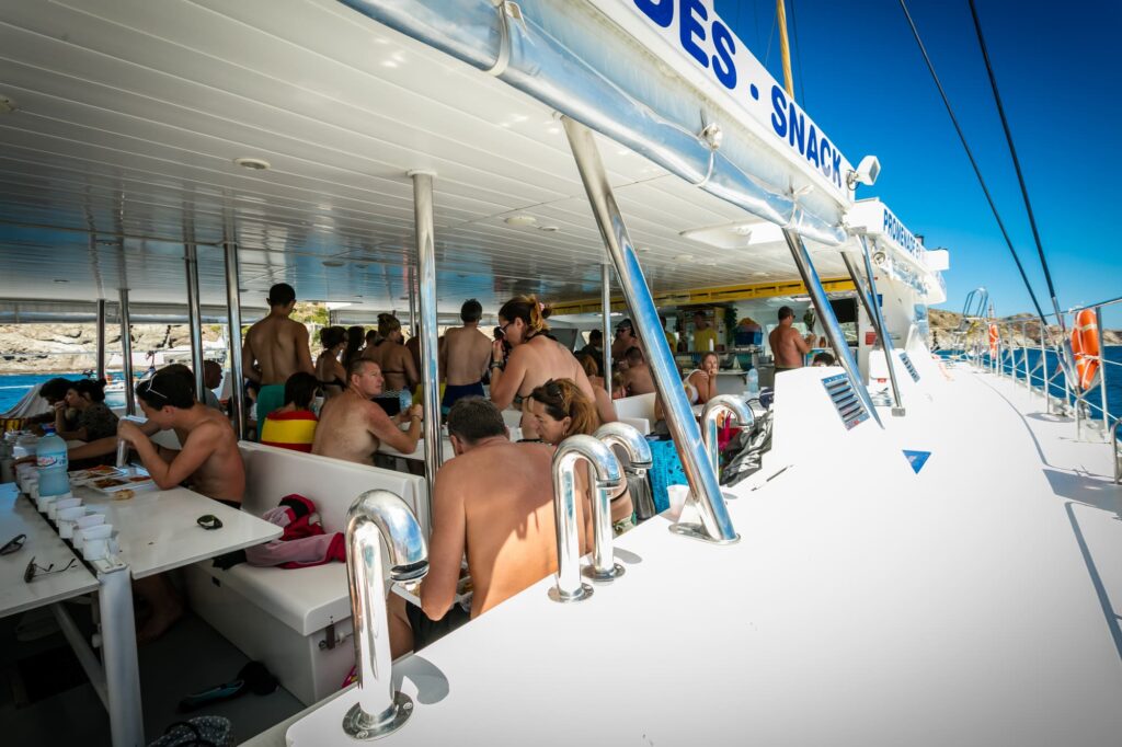 Passagers déjeunant confortablement à l'ombre sur le pont protégé du catamaran Navivoile, profitant d'une brise marine naturelle lors d'une escale gourmande au large de Canet