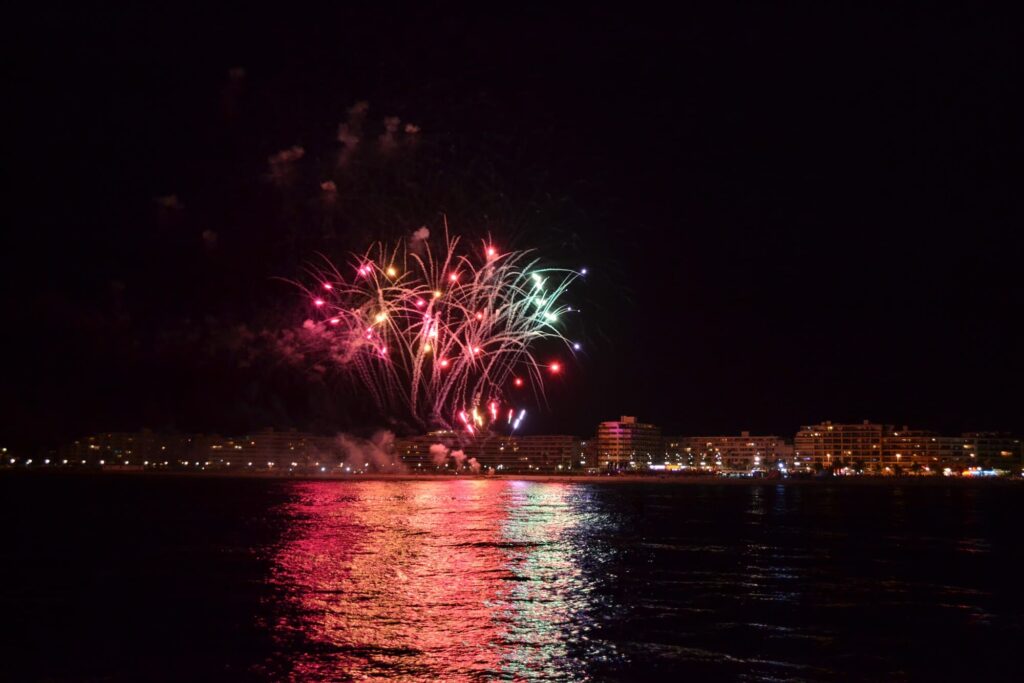 L'ombre du catamaran Navivoile se découpant sur les reflets dorés des feux d’artifice Canet en Roussillon devant la Place Méditerranée