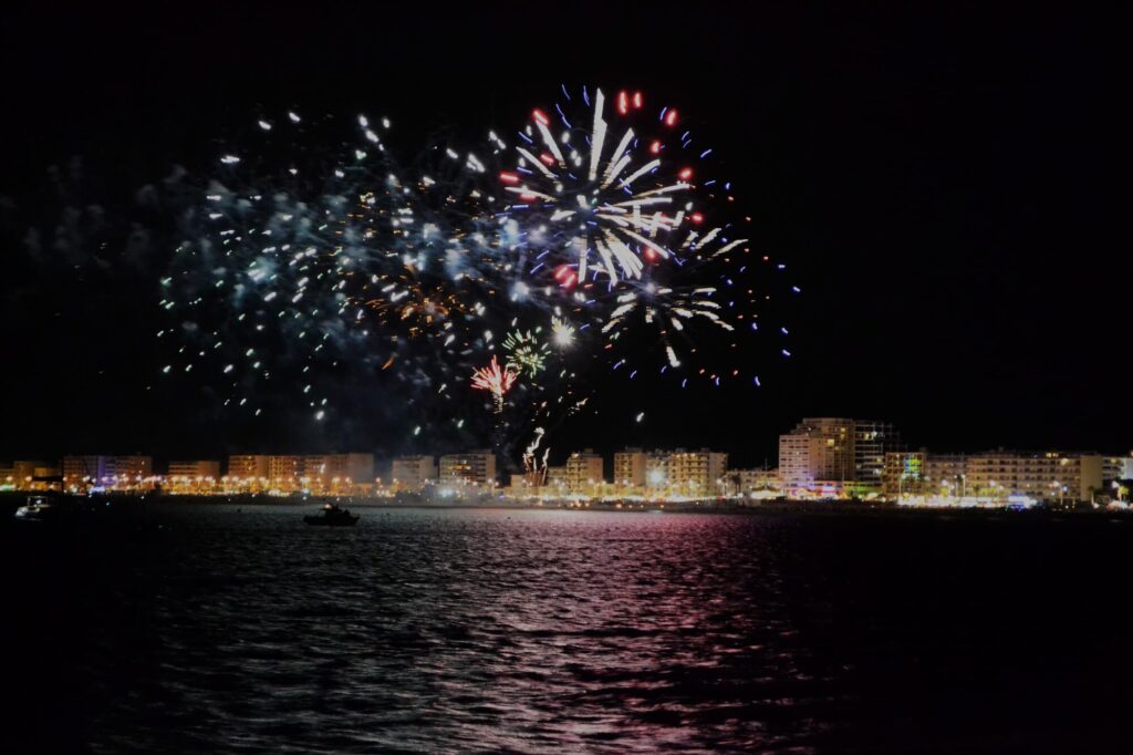 Le catamaran Navivoile naviguant sous une pluie d'étincelles lors du show des feux d’artifice Canet en Roussillon devant la Place Méditerranée