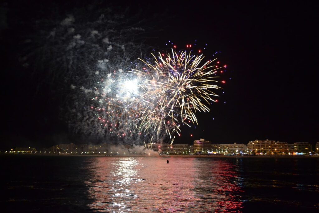Panorama nocturne depuis le large montrant le catamaran Navivoile face aux cascades de lumière des feux d’artifice Canet en Roussillon