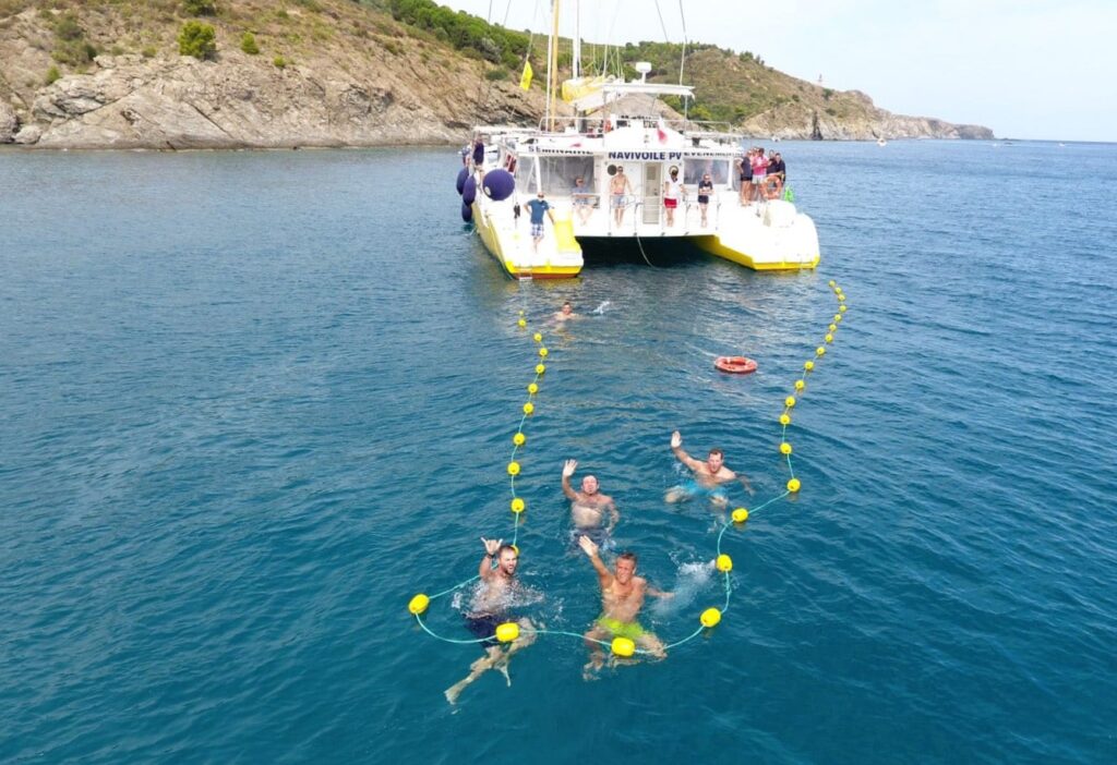 Petit groupe profitant d'une baignade privée à l'arrière du catamaran NAVIVOILE, au mouillage devant les rochers de la baie de Paulilles lors d'une activité pour groupe