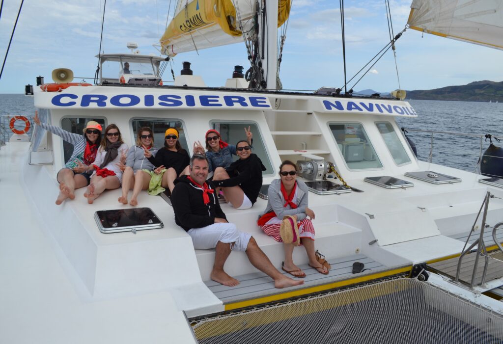 Groupe d'amies célébrant un EVJF à l'avant du catamaran NAVIVOILE sous voiles, lors d'une activité pour groupe au large de Leucate et Barcarès