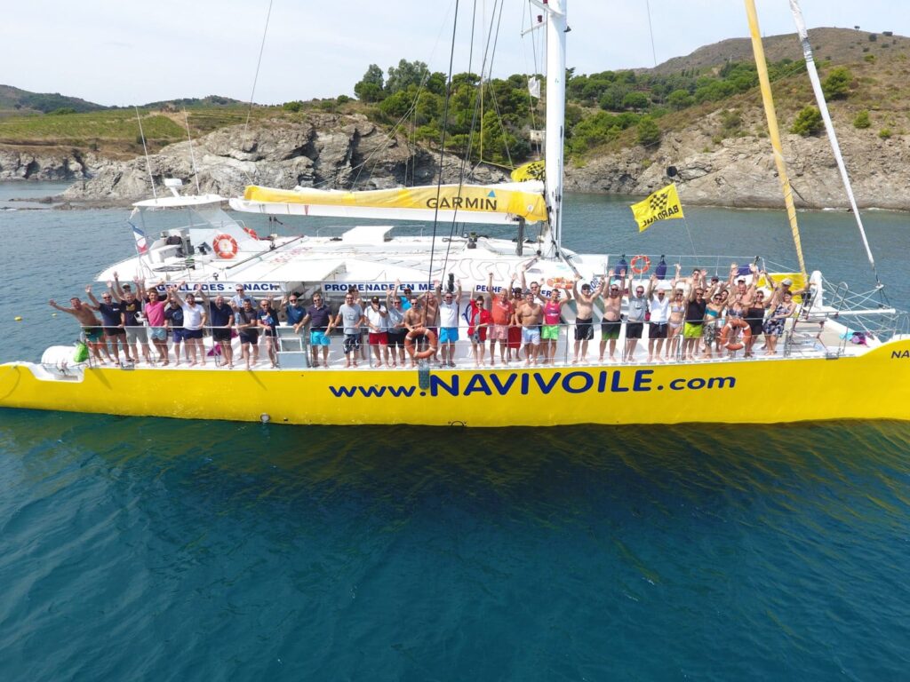 Groupe en voyage incentive saluant le drone depuis le pont du NAVIVOILE au mouillage à Paulilles, une activité pour groupe mémorable