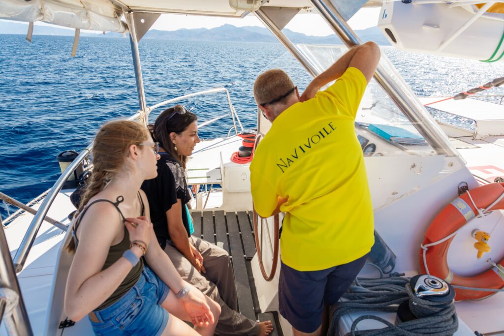Le capitaine du Navivoile explique le fonctionnement des appareils de navigation à deux étudiantes au large de Saint-Cyprien