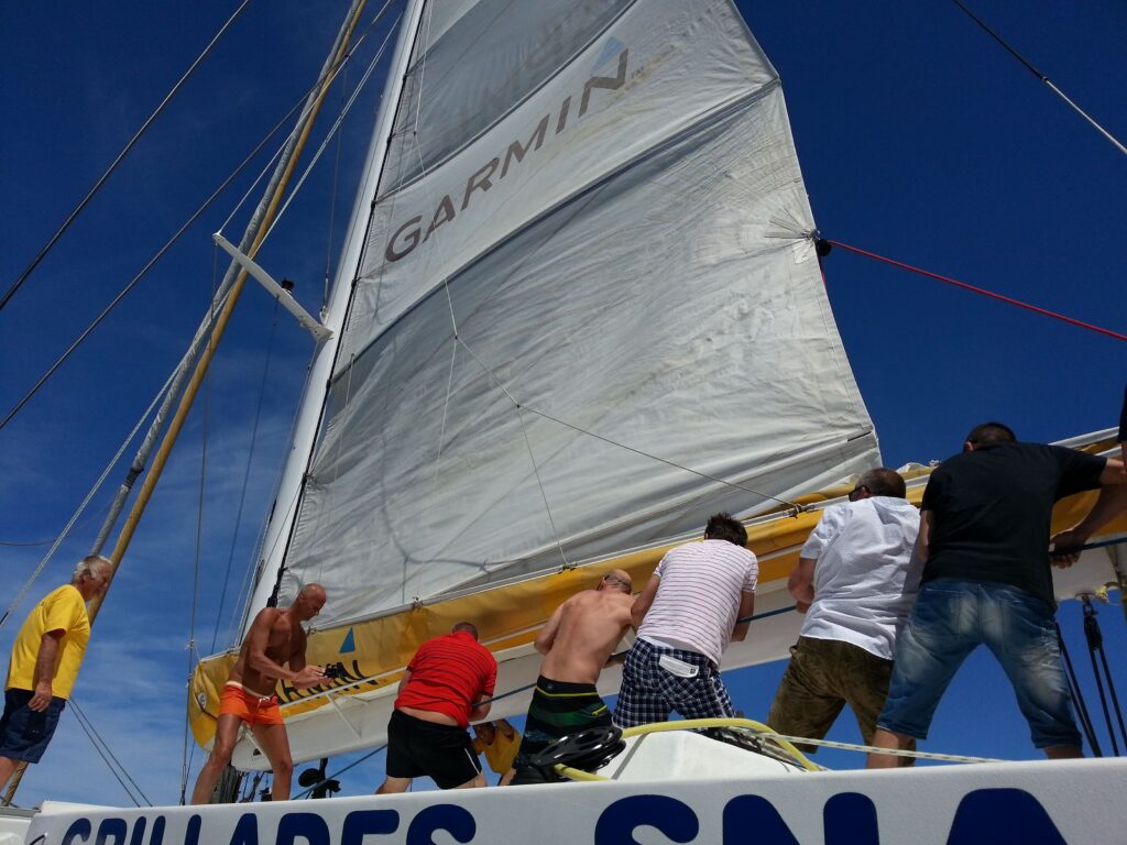 Équipe en team building participant à la manœuvre des voiles lors d'un séminaire en catamaran privatif au large de Saint-Cyprien sur le NAVIVOILE